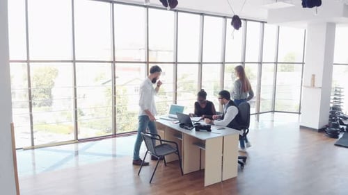 Beautiful stylish staff sitting in the office at the desk using a laptop and listening to a colleagu