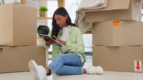 Woman Using Tablet Surrounded by Moving Boxes