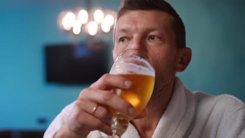 Frontansicht: Porträt eines selbstbewussten, gutaussehenden kaukasischen Mannes, der drinnen erfrischendes Bier trinkt