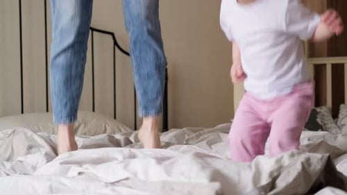 Child and Adult Jumping Joyfully on Bed