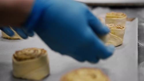 Kitchen in a bakery the process of making cinnabons, a woman baker puts the dough on a baking sheet