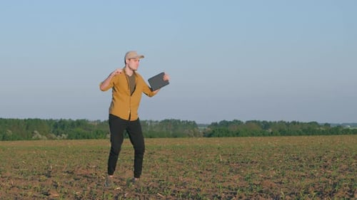 A Young Ermer with a Tablet in His Hand Dances in a Field
