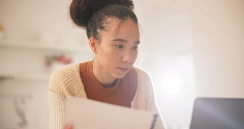Woman Reviews Document at Computer Inside Home
