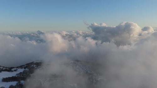 Aerial View of Snow-Covered Mountains Amidst Clouds