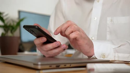 Un travailleur de l'analyse et de l'analyse tient un smartphone moderne en main lorsqu'il travaille à domicile
