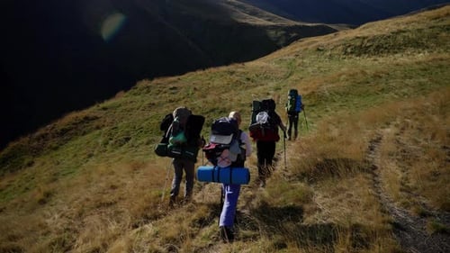 Group of Hikers are Trekking Up a Mountain Trail They are Carrying Backpacks and Hiking Poles The