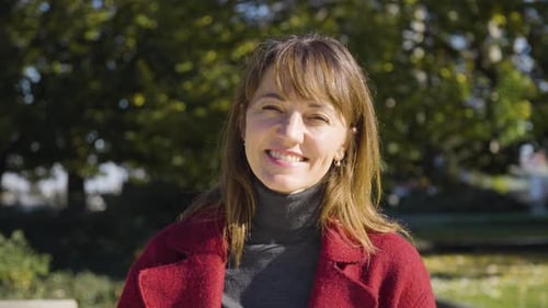 An Attractive Middleaged Caucasian Woman Smiles at the Camera in a Park Ends in Closeup