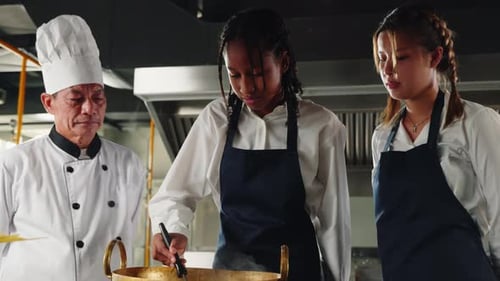 Chef in Kitchen educa a las estudiantes, colegialas en uniforme, a hacer fideos japoneses para niños en la estufa con