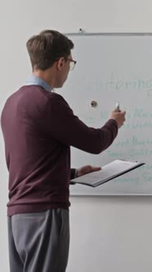 Vertical of Male Team Lead Presenting Collaboration Plan on Whiteboard at Office