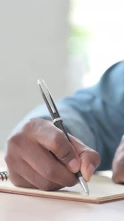 Close Up of Young African Man Writing on Notebook, Vertical Video