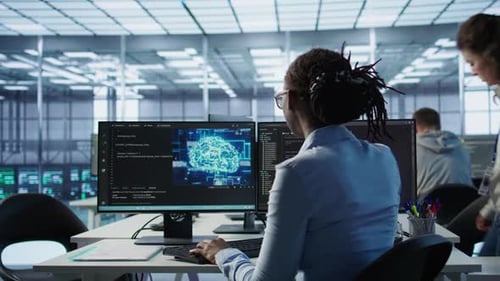 Woman Coding With Brain Graphic on Monitor