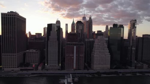 Sunset sun glimpsing through skyscrapers, in New York, USA - tracking Aerial view