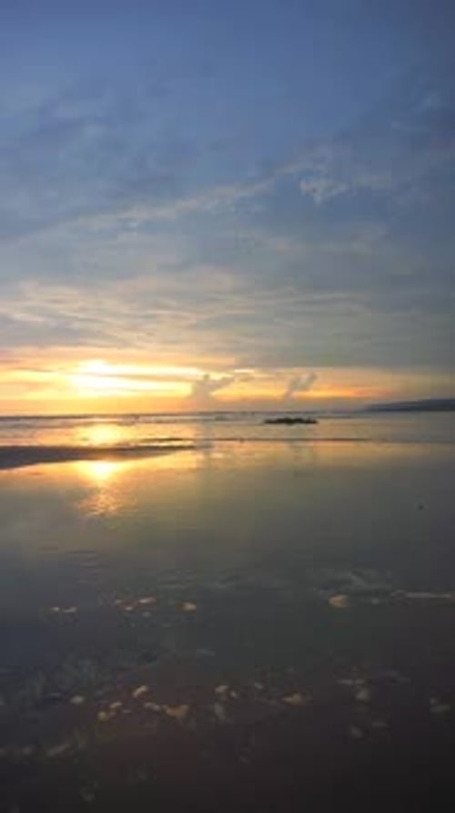 vertical video of beautiful views of the sunset on the beach with small waves, natural panoramas