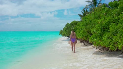 A Girl Walks Along the Shore on the Turquoise Water on the Island of Thoddoo in Maldives