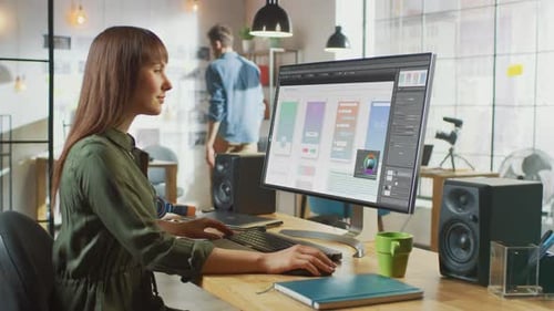 Beautiful Brunette Female Designer Works with Mobile App Interface on Her Personal Computer with Bi