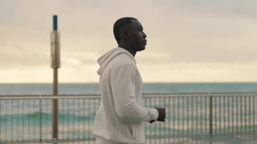 Side view of athlete running along the seaside promenade, cardio workout