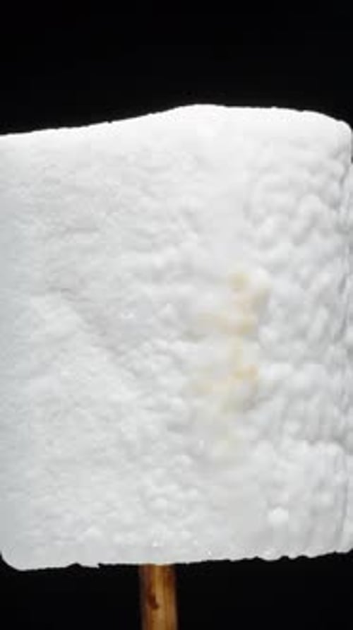 Vertical video. Close-Up Texture of Marshmallow on Stick While Roasting on Fire, Covered.