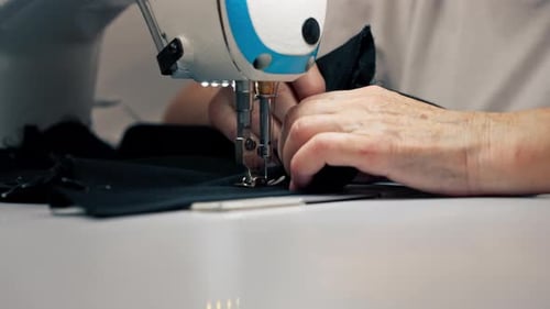 Close Up in a Sewing Workshop on a Machine the Old Seamstress Master Makes Cut on a Black Fabric