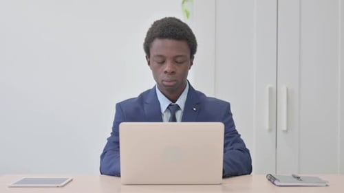Young Adult Works at Laptop in Bright Office