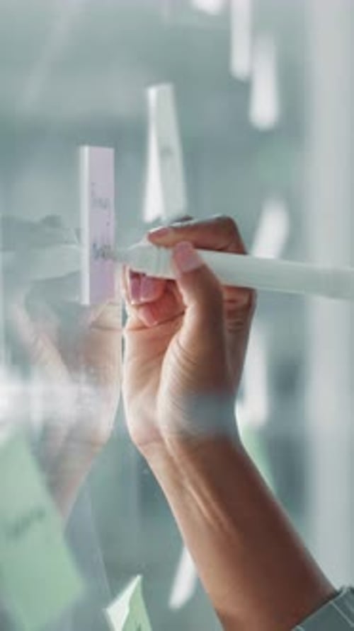 Glass wall, hand and writing with business person in office for brainstorming or strategy
