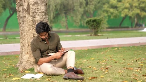 Indischer Student studiert unter einem Baum