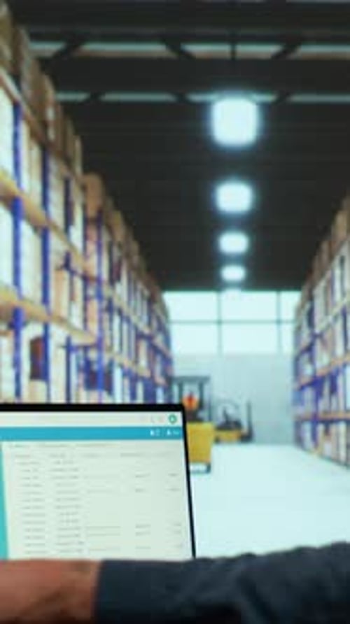 Worker Using Laptop in a Warehouse