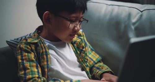 Garçon asiatique portant des lunettes écolier utilisant un ordinateur portable