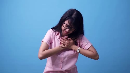 Portrait of Asian woman holding hands on chest feeling acute pain in chest, risk of stroke, heart at