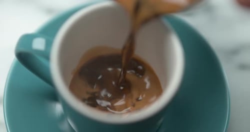 Pouring Rich Coffee Into a White Coffee Cup