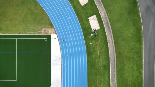 Woman Running on Blue Track Field Seen from Drone