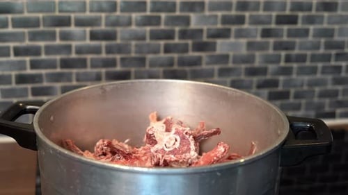 Hand Placing Frozen Bones Into Pot for Stock
