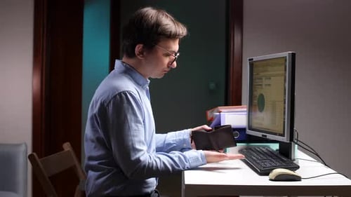 Businessman Finding Empty Wallet at Office Desk Showing Financial Problems