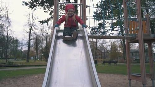 Happy Little Girl Slide Down on a Slide at the Outdoor Playground. Autumn Park Playground Slow