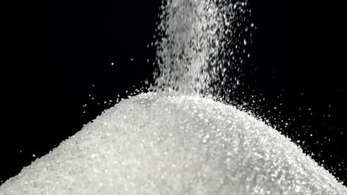 Zucker fällt auf einem Haufen auf den Tisch, gefilmt mit einer Hochgeschwindigkeitskamera mit 1000 Bildern pro Sekunde