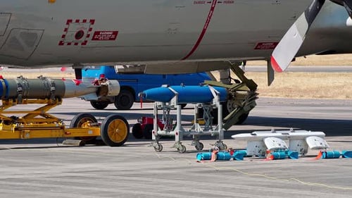 Military Aircraft is Parked on the Tarmac with Various Munitions Including Missiles and Bombs Loaded