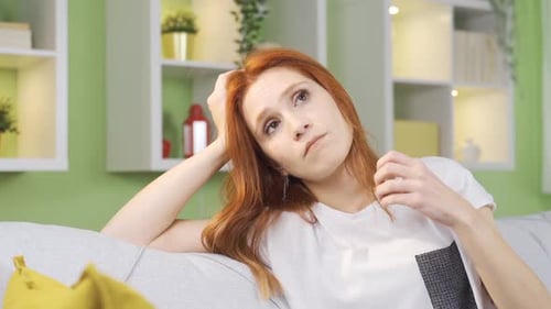 Thoughtful Woman Reclining on Sofa at Home