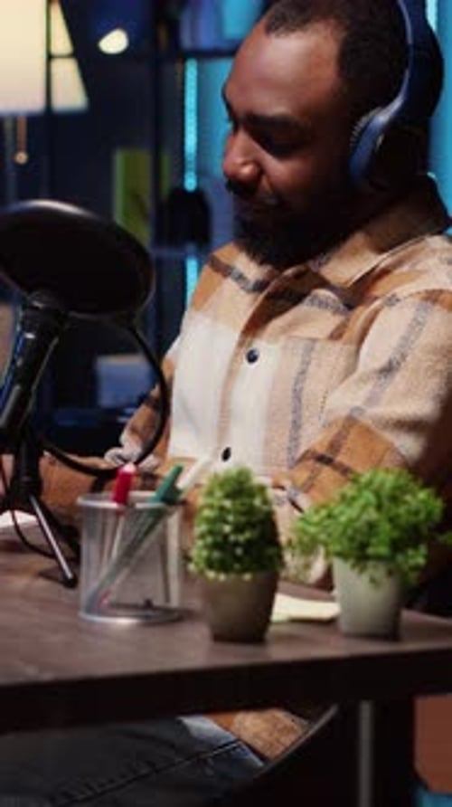 Young Man Podcasting into Microphone at Desk