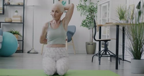 Senior Woman Stretching at Home on Yoga Mat