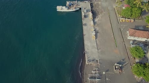 Aerial top view beach white and black volcanic sand with traditional Indonesian boat on the coast in