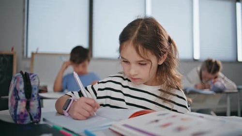 Attentive Schoolgirl Solving Tests Notebook in Elementary School Class Closeup