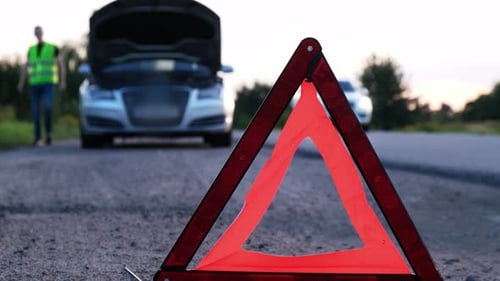 Broken Silver Luxury Car Emergency Accident Man Driver Installing Red Triangle Stop Sign on Road