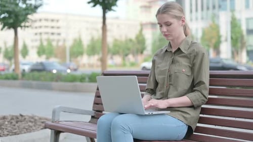 Woman Works on Laptop on City Park Bench