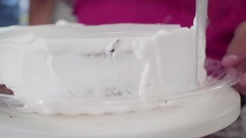Close Up of a homemade cake that is frosted of white. The pastry chef making a delicious glazed choc