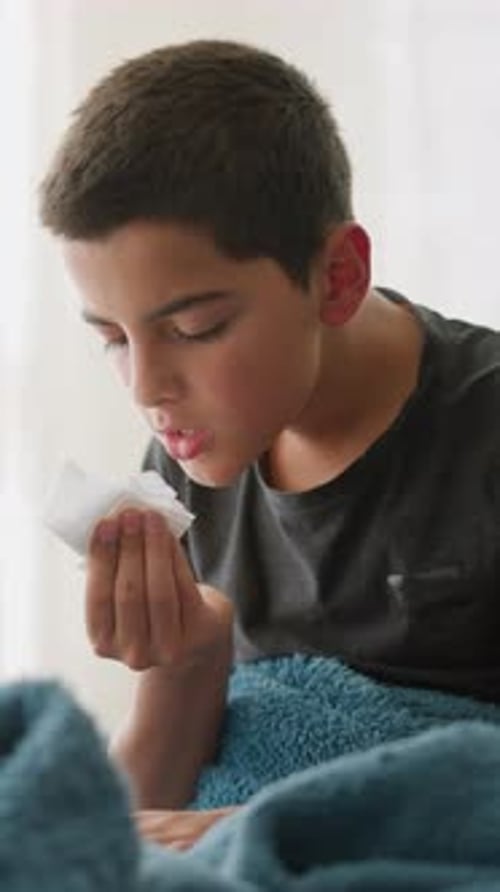 Teenage Boy Blowing Nose with Tissue While Sick