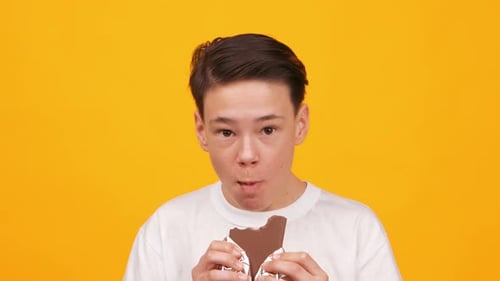 Young Boy Enjoys Chocolate Moment With Bright Yellow Background in Footage