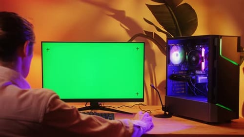 Computer mit Chroma Key, grünem Bildschirm auf dem Monitor, Gamer Man spielt in beliebten Videospielen, Programmierer
