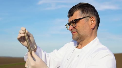 Laboratory Worker Holding Professional Glassware and Testing Black Soil Before Harvest in the Field