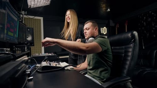 a girl singer and a male sound engineer work together in recording studio to create a new song
