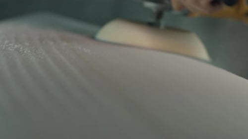 Surf factory. Adult male shaper creates the surfing board on the factory