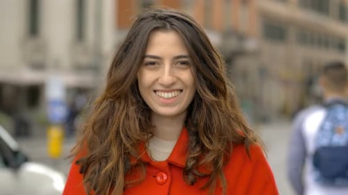 Happy carefree beautiful woman in the street, smiling at camera